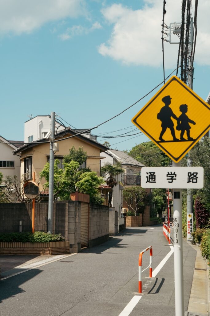 Quiet residential street in Tokyo featuring a school crossing sign, typical suburban scene.